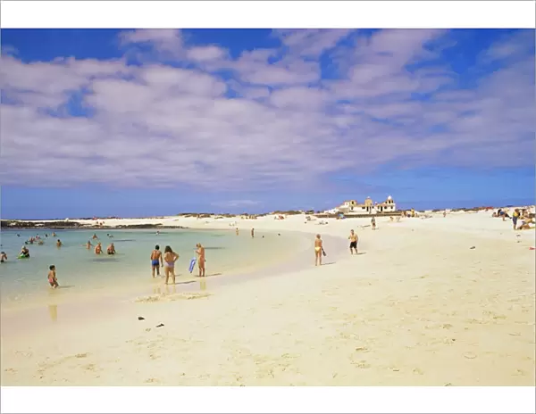 People playing on the beach and natural swimming pool beyond, near El Cotillo