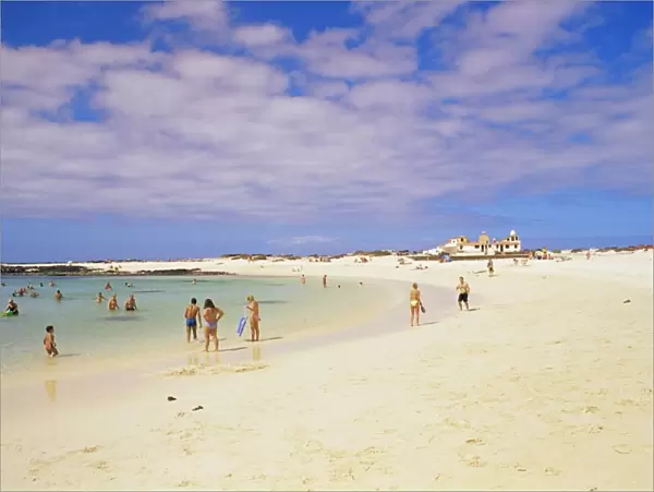 People playing on the beach and natural swimming pool beyond, near El Cotillo