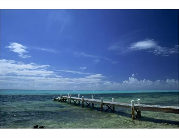 Waves breaking on reef on the horizon, with jetty in foreground, Grand Cayman