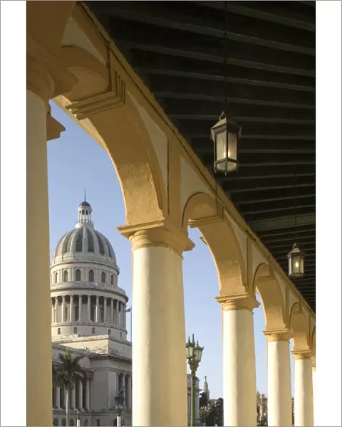 A view of the Capitolio seen through the arches of a colonial style arcade in central Havana