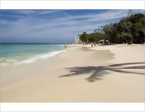 The shadow of a palm tree on the beach and emerald sea. Guardalavaca Beach, Guardalavaca, Cuba, West Indies, Central