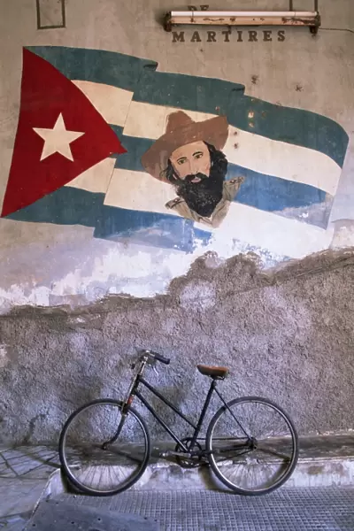 Mural of Camilo Cienfuergos on wall above a bicycle, Havana, Cuba, West Indies