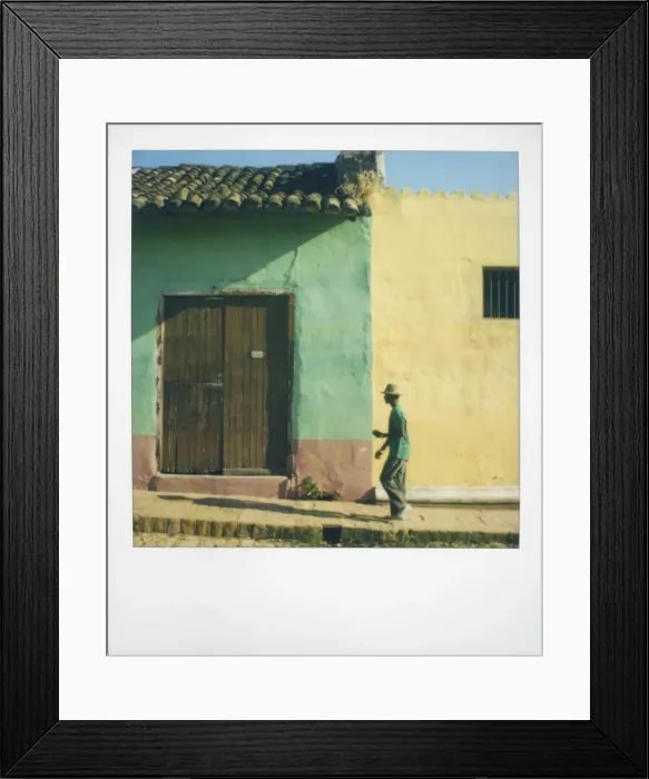 Framed Print : Polaroid of man walking along street against houses painted green and yellow Framed Print : Polaroid of man walking along street against houses painted green and yellow