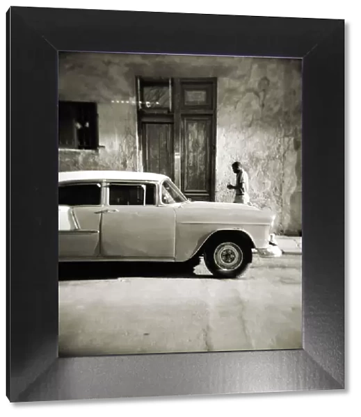Image taken with a Holga medium format 120 film toy camera of man walking past old American car