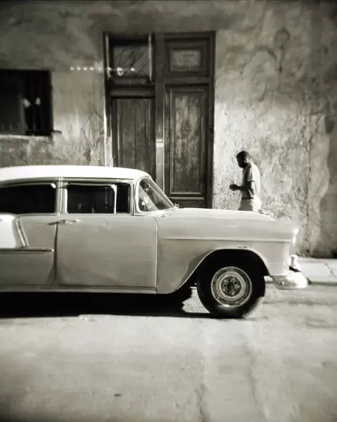 Image taken with a Holga medium format 120 film toy camera of man walking past old American car