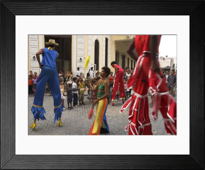 Framed Print : Group of people on stilts and in colourful costumes dancing and juggling in the street Framed Print : Group of people on stilts and in colourful costumes dancing and juggling in the street
