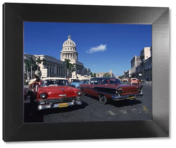 Street scene of old American automobiles used as taxis parked near the Capitolio Building in Central Havana, Cuba, West Indies