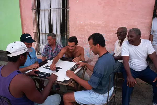 A group of men sitting around a table playing dominoes outdoors, Trinidad