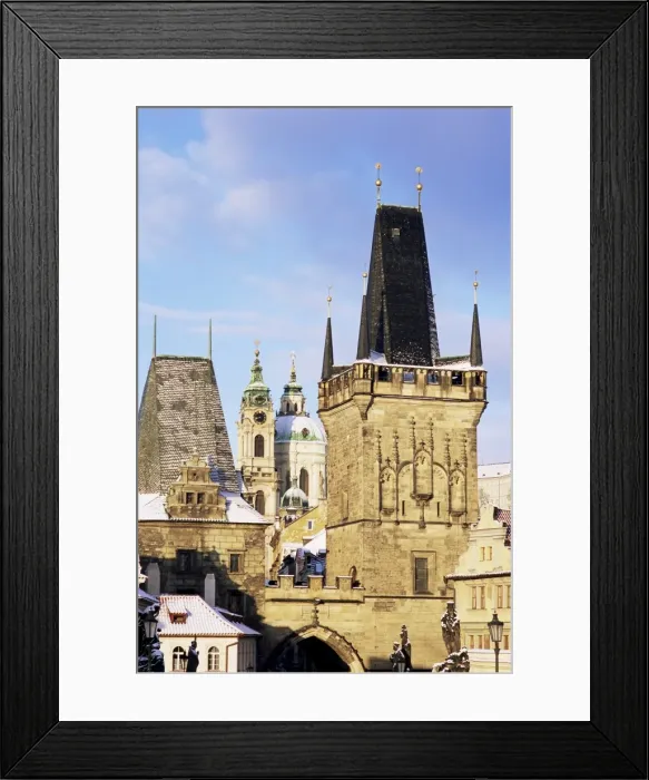 Framed Print : Snow-covered Romanesque and Gothic Malostranske Bridge towers and in the background the towers of the Baroque St. Nicholas church, Mala Strana, Prague, Czech