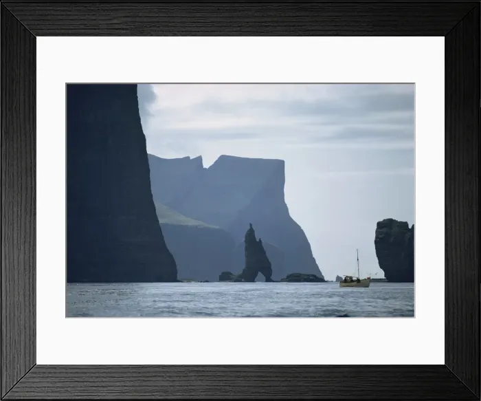Framed Print : Small fishing boat before a towering cliff coastline, Faroe Islands, Denmark Framed Print : Small fishing boat before a towering cliff coastline, Faroe Islands, Denmark