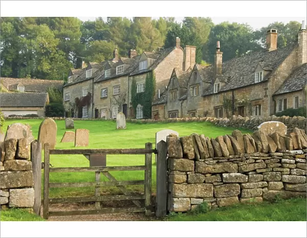 Dry stone wall, gate and stone cottages, Snowshill village, The Cotswolds