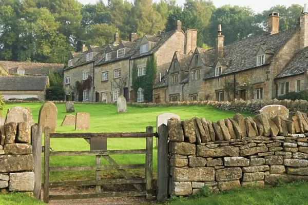 Dry stone wall, gate and stone cottages, Snowshill village, The Cotswolds
