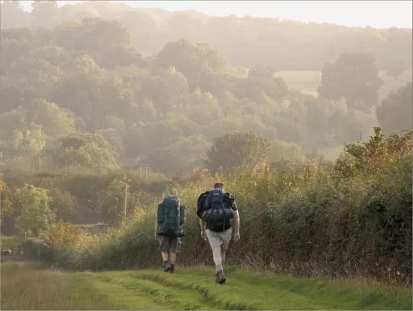 Two walkers with rucksacks on the Cotswold Way footpath, Stanway village