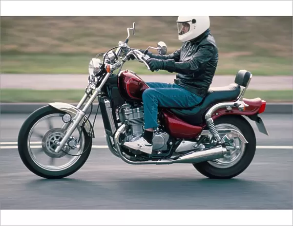 Motorcyclist rides Suzuki twin motorcycle on highway, Dawlish, Devon, England