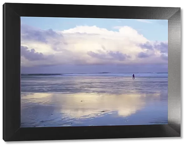Beach at Embleton Bay with lone walker, dramatic clouds and reflections in wet sand
