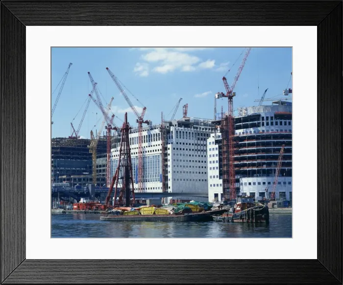 Framed Print : Skips on barges and cranes in front of buildings under construction in the Docklands Framed Print : Skips on barges and cranes in front of buildings under construction in the Docklands