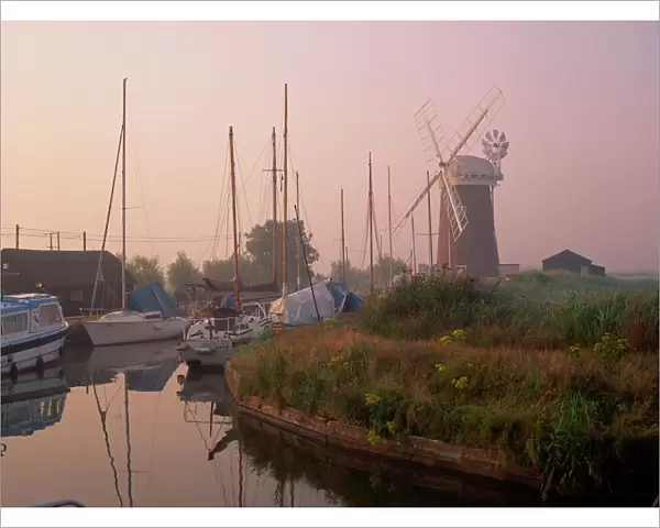 Horsey Wind Pump and boats moored on the Norfolk Broads at dawn, Norfolk