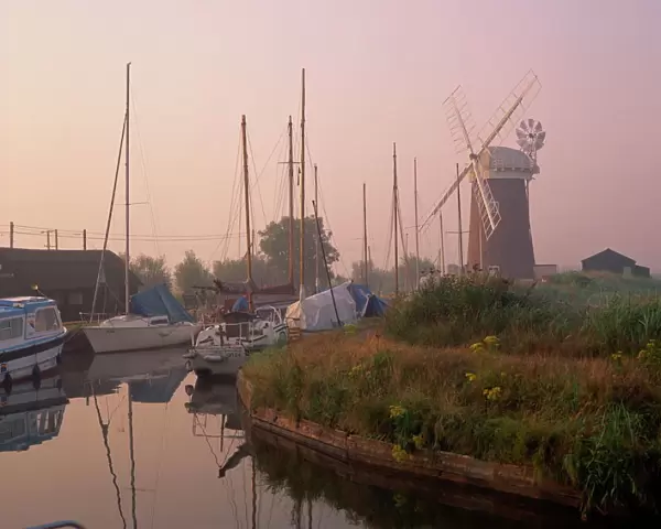 Horsey Wind Pump and boats moored on the Norfolk Broads at dawn, Norfolk