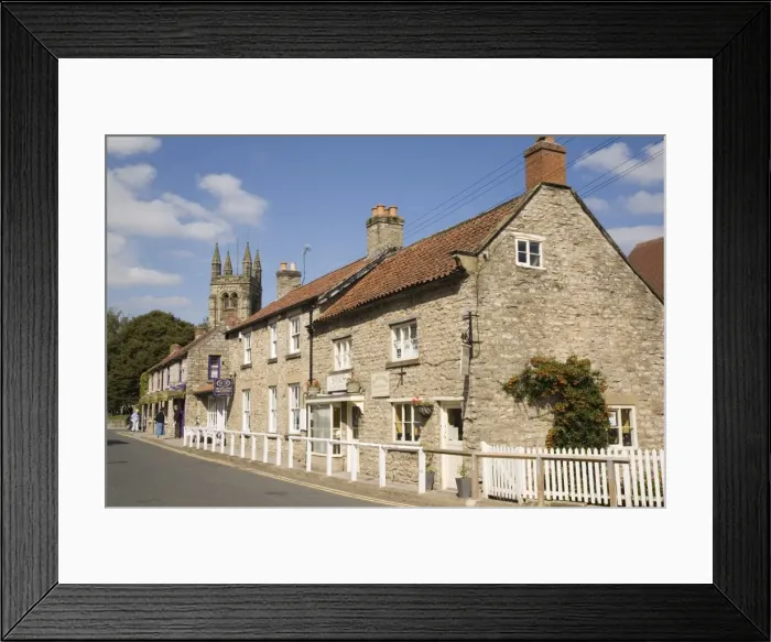 Framed Print : Traditional sandstone cottages and shops with tower of All Saints Church Framed Print : Traditional sandstone cottages and shops with tower of All Saints Church