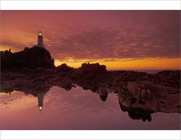 Dramatic sunset and low tide, Corbiere lighthouse, St. Ouens, Jersey, Channel Islands