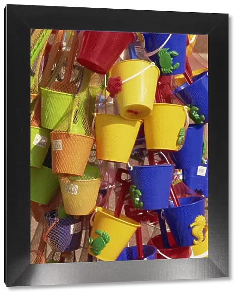 Fifteen brightly coloured buckets, mainly yellow and blue, for sale, Skegness