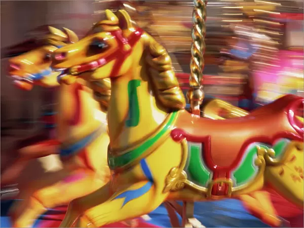 Motion blur of brightly painted merry go round (carousel) horses at speed