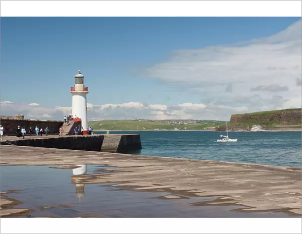 Lighthouse at entrance to outer harbour, motor yacht entering, Whitehaven