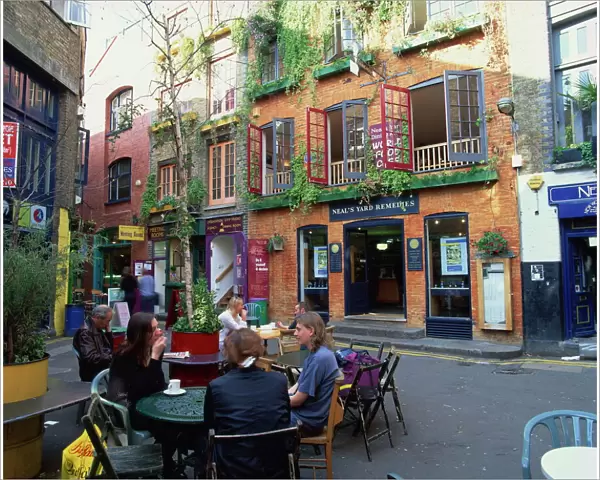 Small group of people sitting outdoors at tables of a cafe in Neals Yard