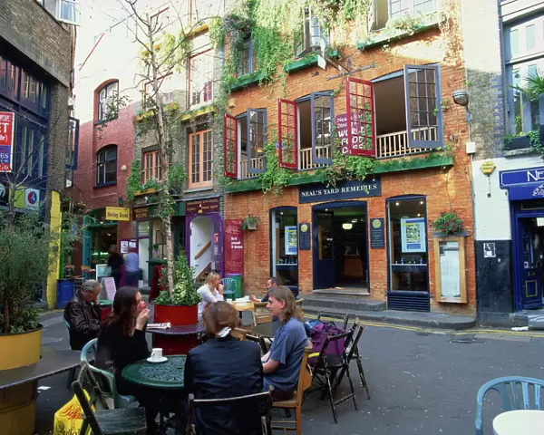 Small group of people sitting outdoors at tables of a cafe in Neals Yard