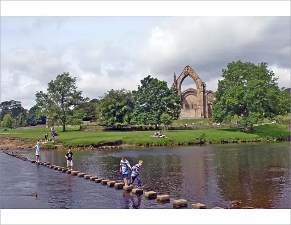 Children crossing the stepping stones across the river Wharfe at Bolton Abbey