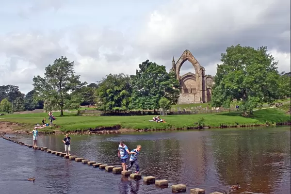 Children crossing the stepping stones across the river Wharfe at Bolton Abbey