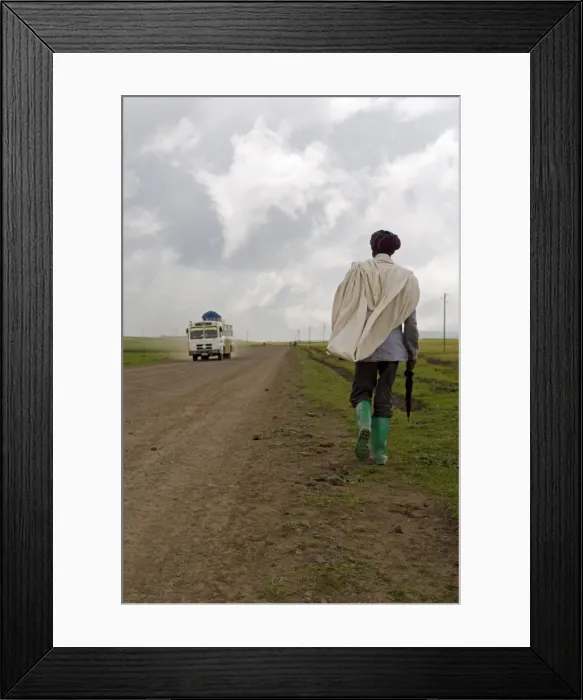Framed Print : Man walking along the road during the rainy season wearing green boots Framed Print : Man walking along the road during the rainy season wearing green boots