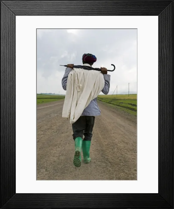 Framed Print : Man walking along the road during the rainy season wearing green boots Framed Print : Man walking along the road during the rainy season wearing green boots