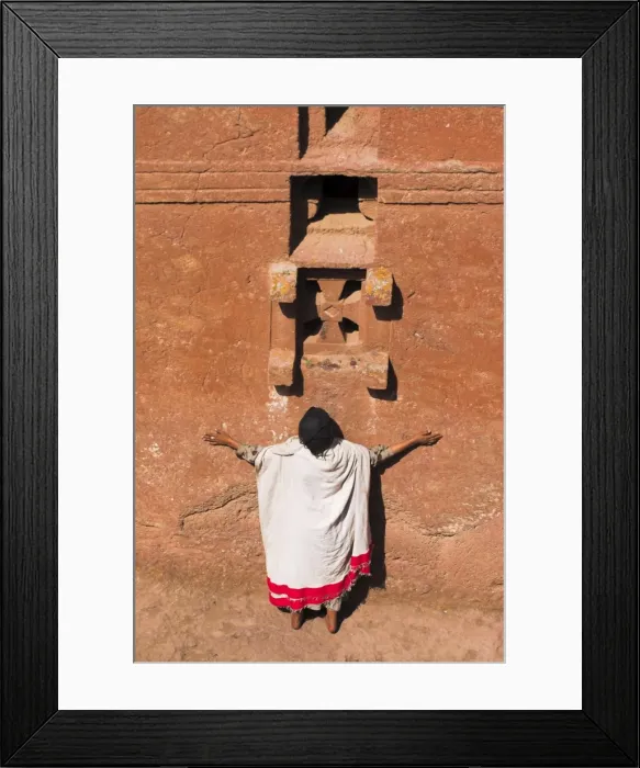 Framed Print : Pilgrim with arms outstretched praying under windows on monolithic church of Bet Maryam church Framed Print : Pilgrim with arms outstretched praying under windows on monolithic church of Bet Maryam church