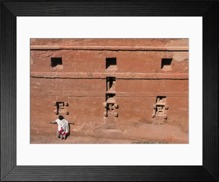 Framed Print : Pilgrim with arms outstreched standing under windows on monolithic church of Bet Maryam church Framed Print : Pilgrim with arms outstreched standing under windows on monolithic church of Bet Maryam church