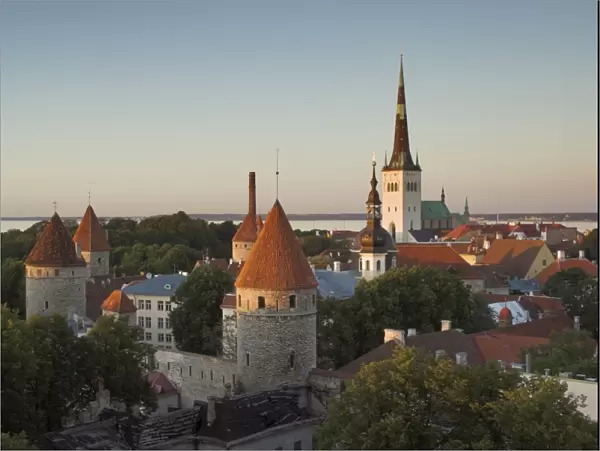 Medieval town walls and spire of St. Olavs church at dusk, Tallinn, Estonia