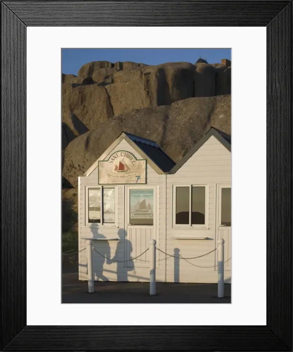 Framed Print : Shadow of couple walking past beach huts in front of granite boulders, Tregastel Framed Print : Shadow of couple walking past beach huts in front of granite boulders, Tregastel