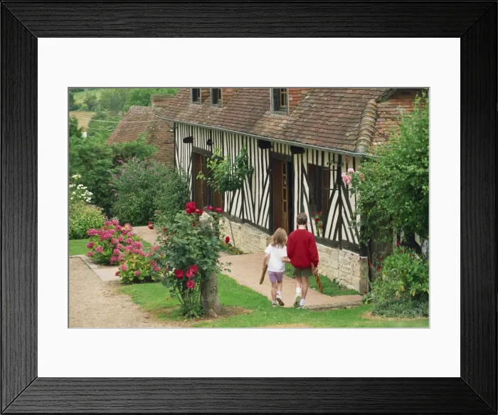 Framed Print : Children carrying baguettes in front of a typical half timbered cottage near St