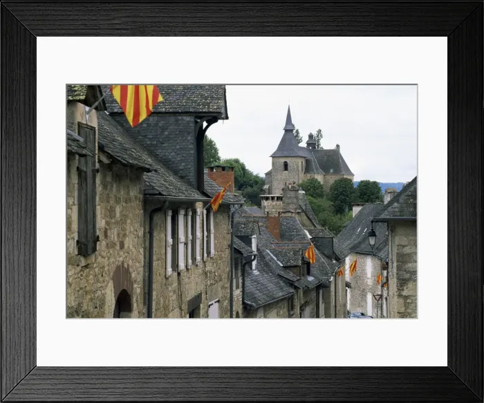Framed Print : View along village street to church, with colourful flags, Turenne, Correze Framed Print : View along village street to church, with colourful flags, Turenne, Correze