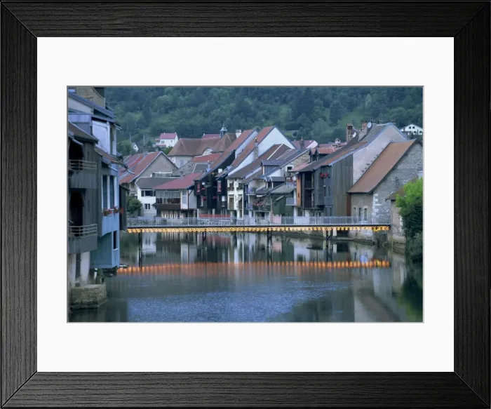 Framed Print : Footbridge illuminated at dusk and houses along the Loue River, Ornans Framed Print : Footbridge illuminated at dusk and houses along the Loue River, Ornans