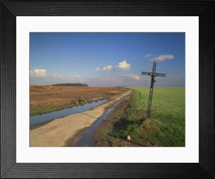 Framed Print : Metal crucifix beside a muddy rural road through agricultural land, near Azincourt Framed Print : Metal crucifix beside a muddy rural road through agricultural land, near Azincourt