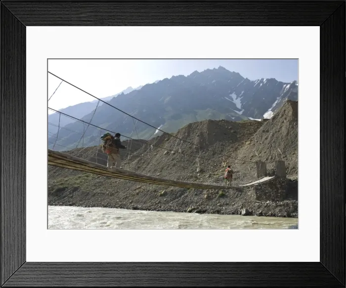 Framed Print : Two men carrying backpacks crossing a wooden suspended Framed Print : Two men carrying backpacks crossing a wooden suspended