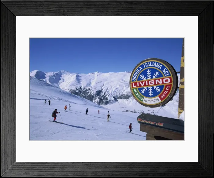 Framed Print : Livigno sign with skiers and mountains in the background Framed Print : Livigno sign with skiers and mountains in the background