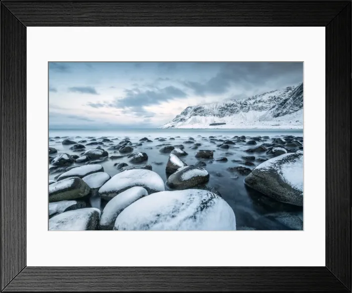 Framed Print : Rocks in the cold sea and snow capped mountains under the blue light of dusk, Unstad