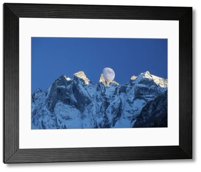 Framed Print : The moon appears behind the snowy mountains illuminating the peaks at sunset, Bondasca Valley Framed Print : The moon appears behind the snowy mountains illuminating the peaks at sunset, Bondasca Valley