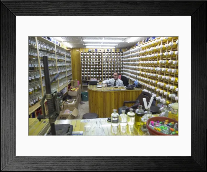 Framed Print : Shop owner surrounded by shelves of hundreds of perfume flasks Framed Print : Shop owner surrounded by shelves of hundreds of perfume flasks