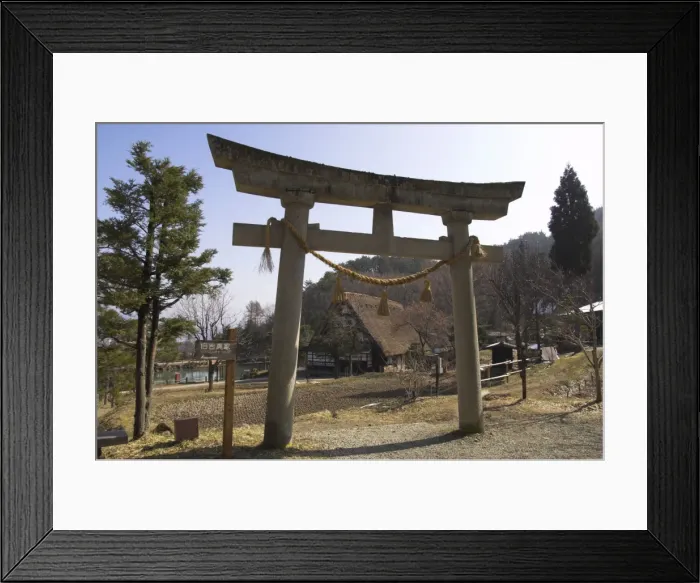 Framed Print : Backlit Shinto torii with traditional house beyond Framed Print : Backlit Shinto torii with traditional house beyond