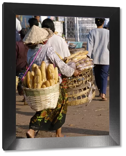 Woman carrying two baskets of French bread in the Talaat