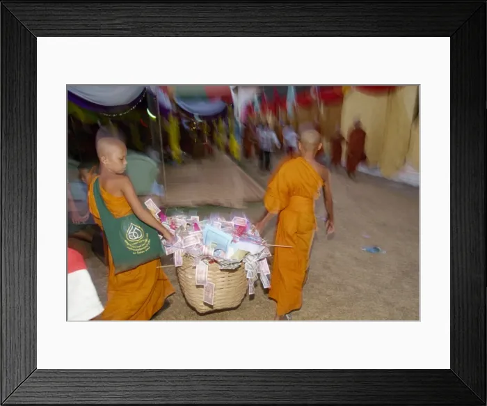 Framed Print : Two young monks carrying basket of donations during Framed Print : Two young monks carrying basket of donations during