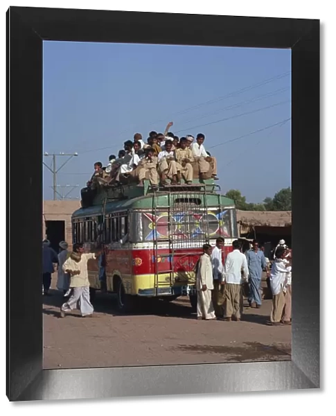 Overloaded bus with men riding on the roof near Multan in Pakistan
